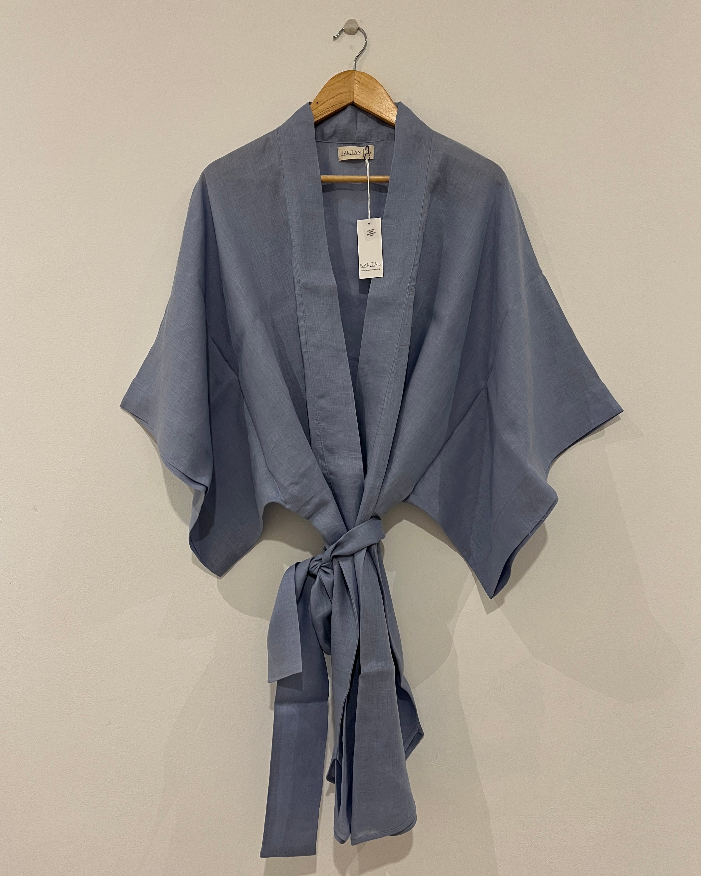 A light blue kimono robe with extra wide sleeves and a waist tie, displayed on a hanger against a white background.