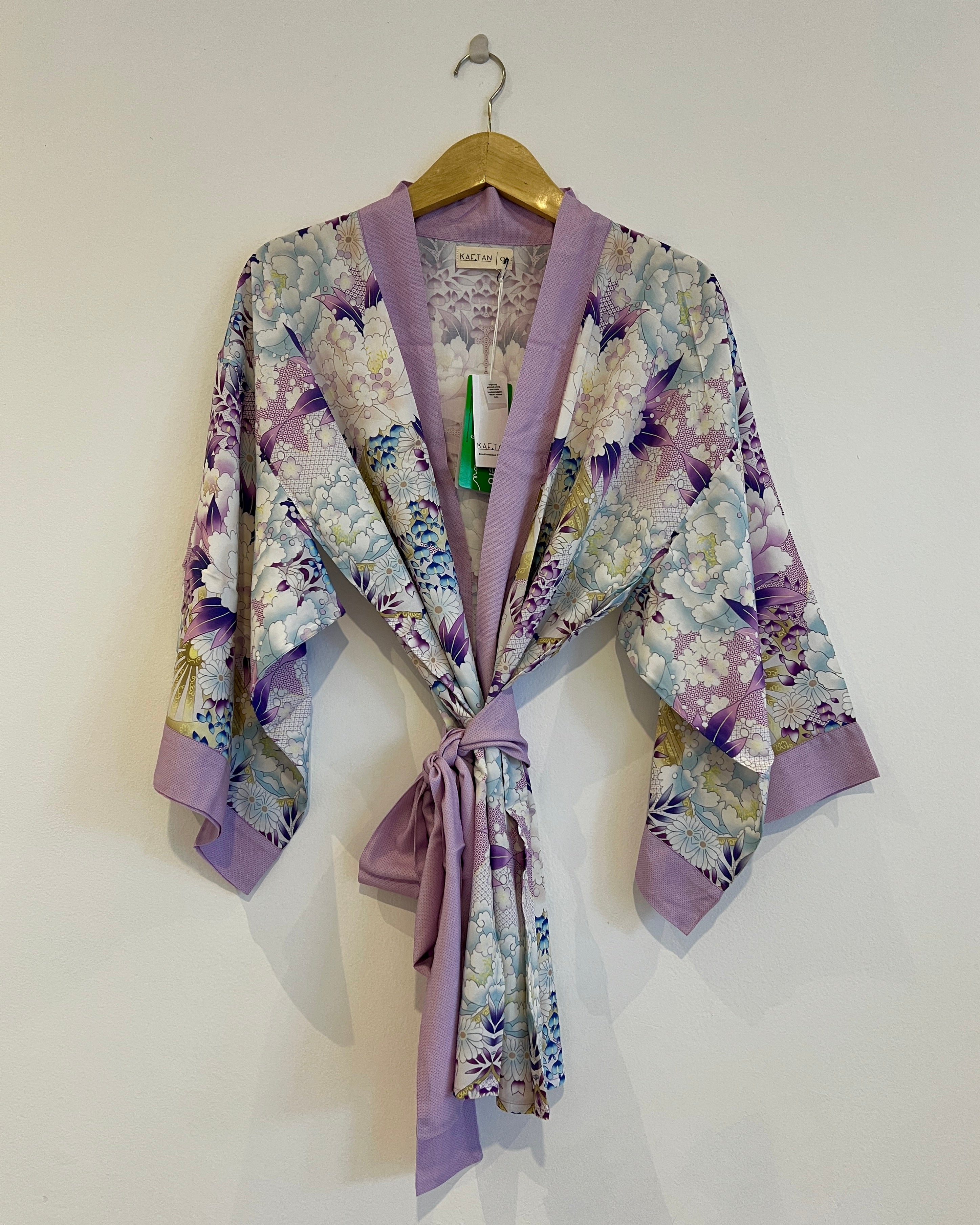 A violet and blue floral kimono with wide sleeves and a detachable waist tie, displayed on a hanger.