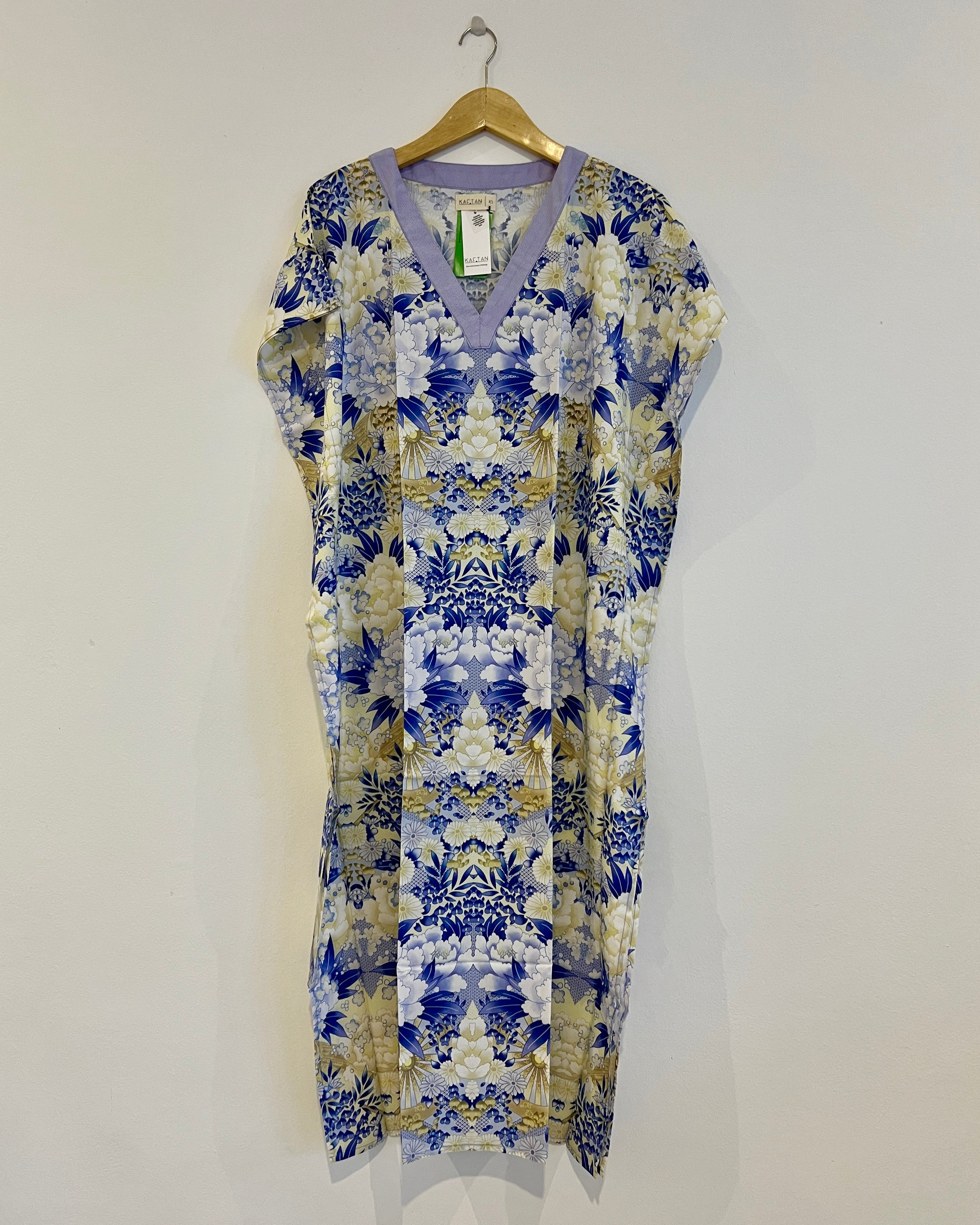 A long kaftan with a floral pattern in blue and yellow colors, displayed on a hanger.