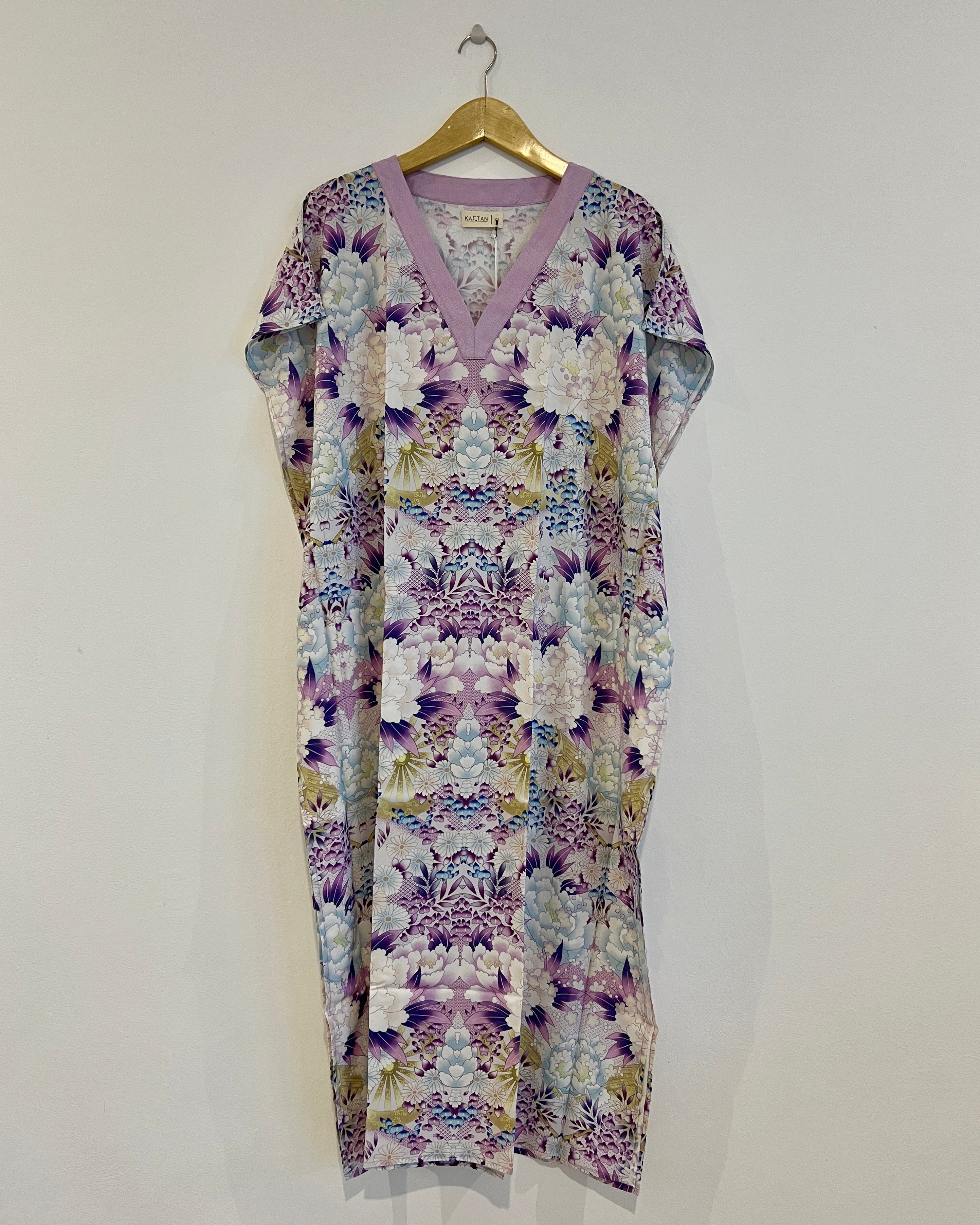 A long kaftan dress with a violet and blue floral print, displayed on a hanger.