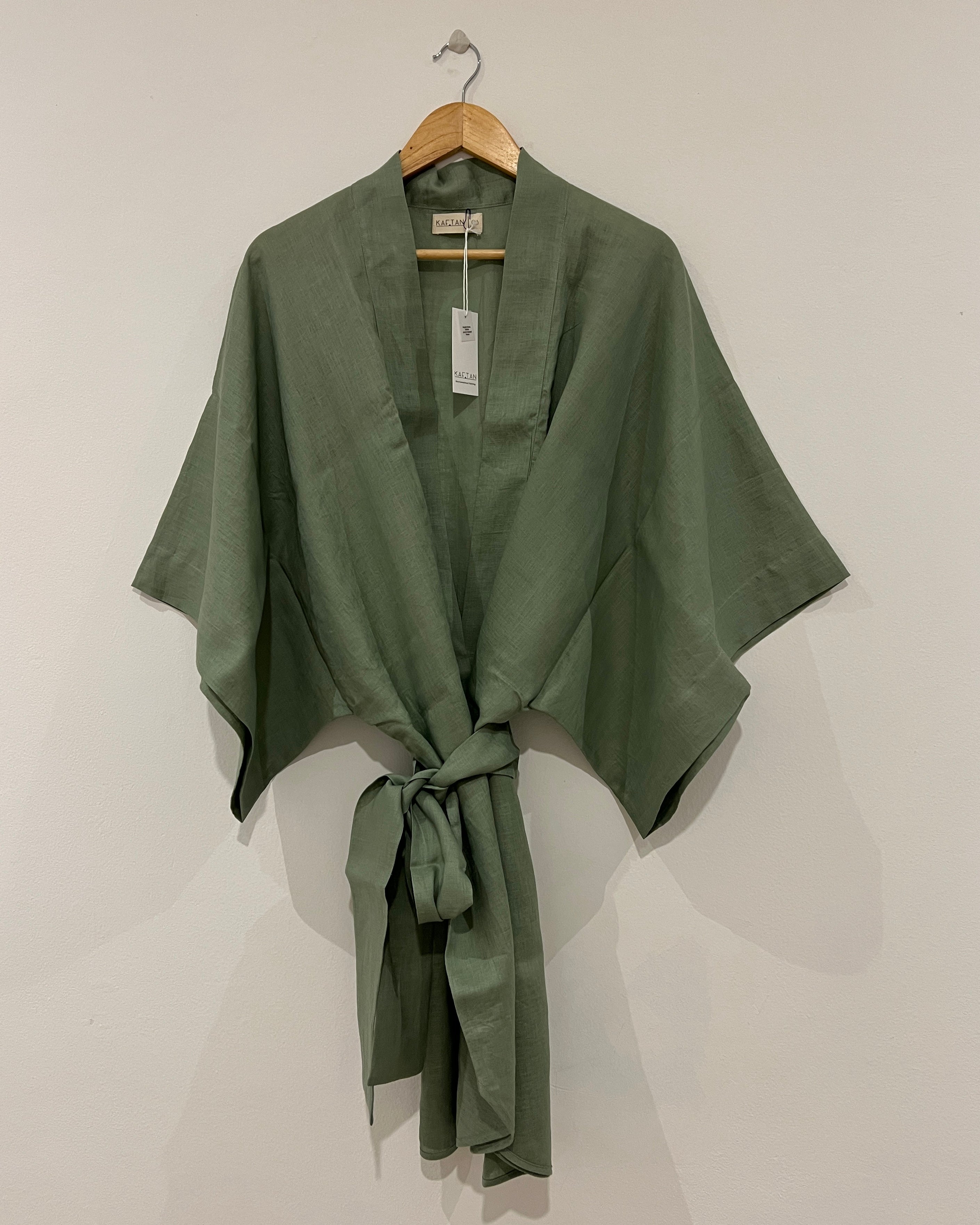 A green kimono robe with extra wide sleeves and a waist tie, displayed on a hanger against a white background.