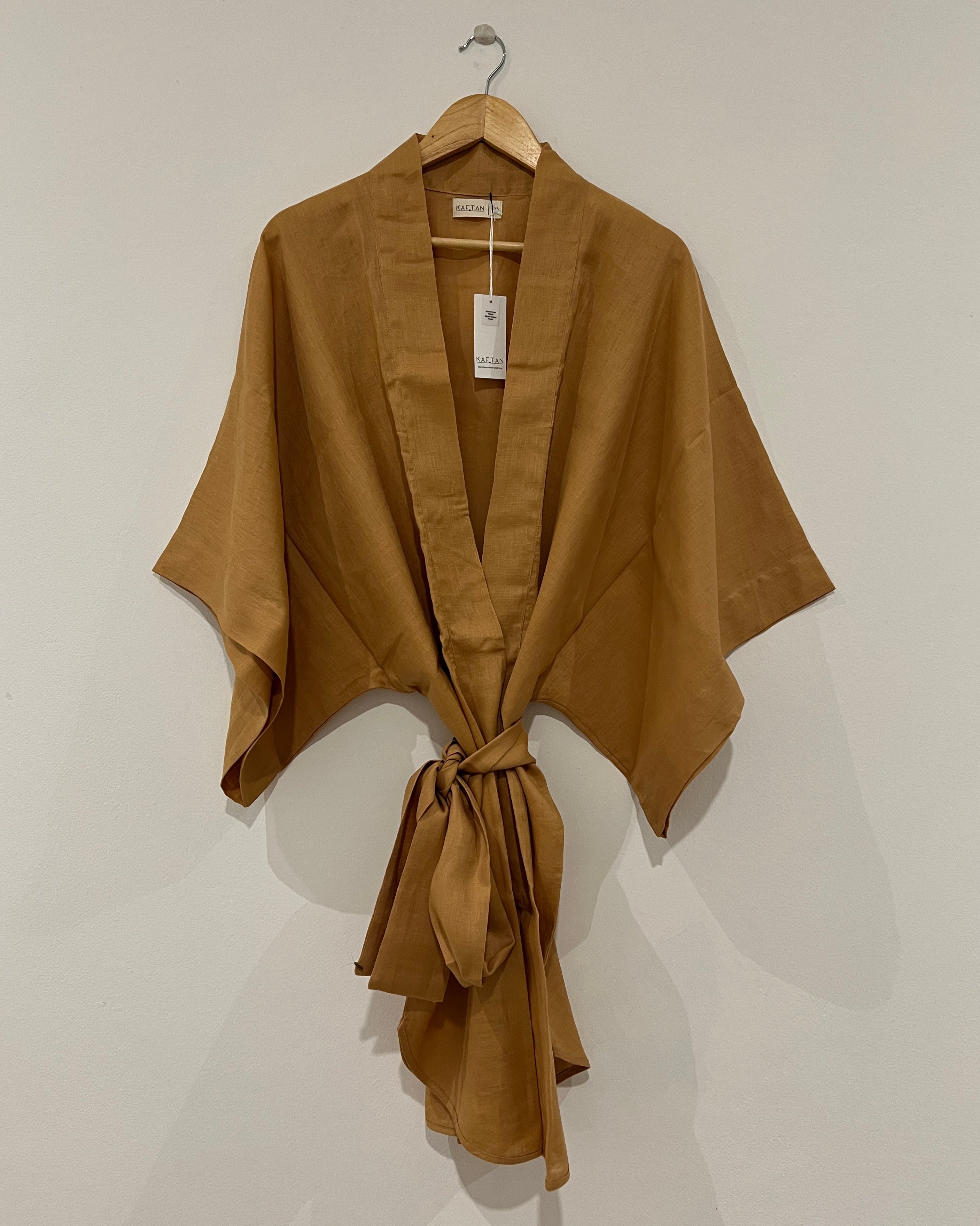 A brown orange kimono robe with extra wide sleeves and a waist tie, displayed on a hanger against a white background.